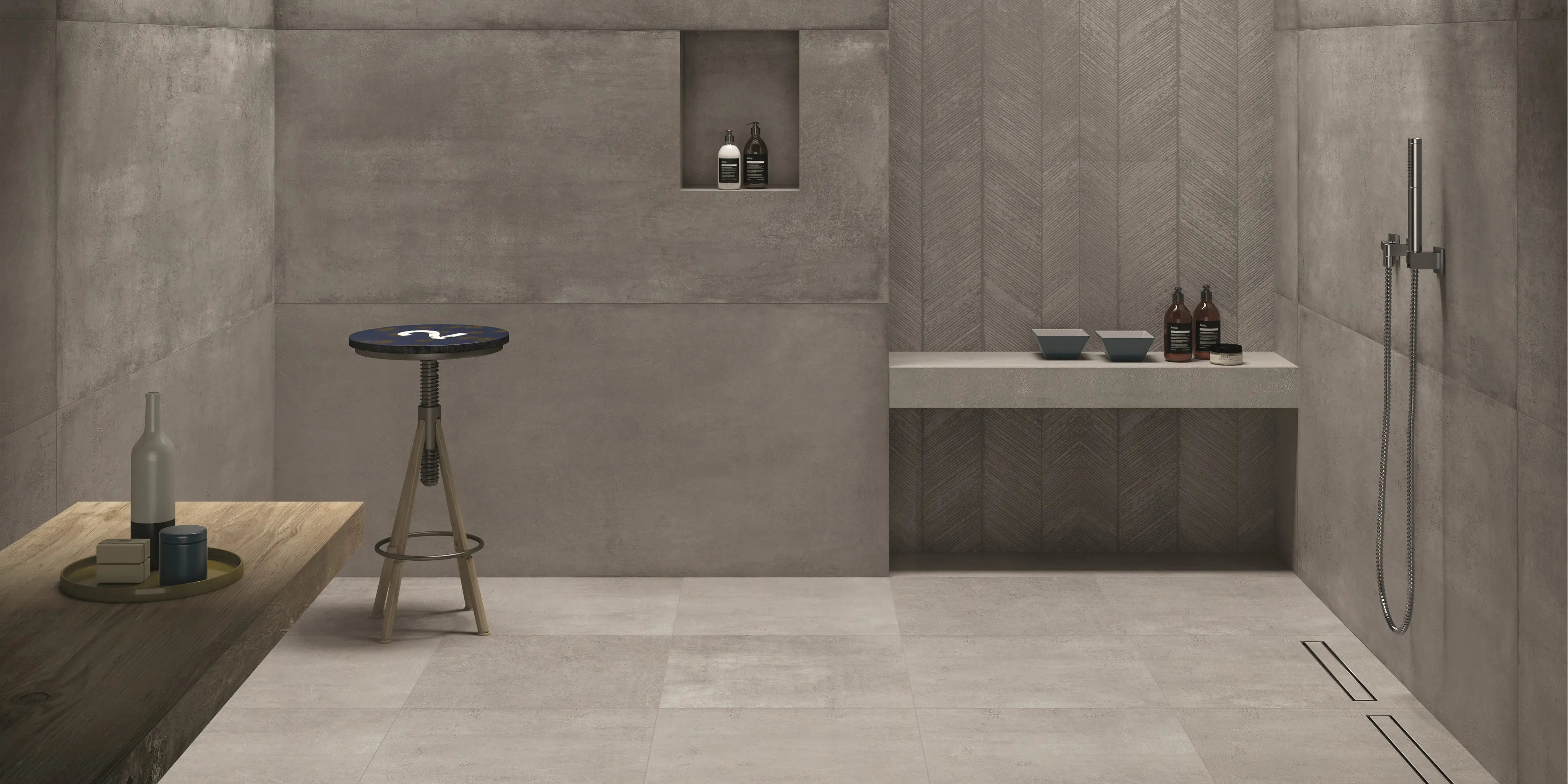 Rå cementlook fliser i 80x180 på væg og 60x60 på gulvet for et moderne urbant udtryk. En bænk af fliser i brusenichen for med badesæbe for et minimalistisk look.